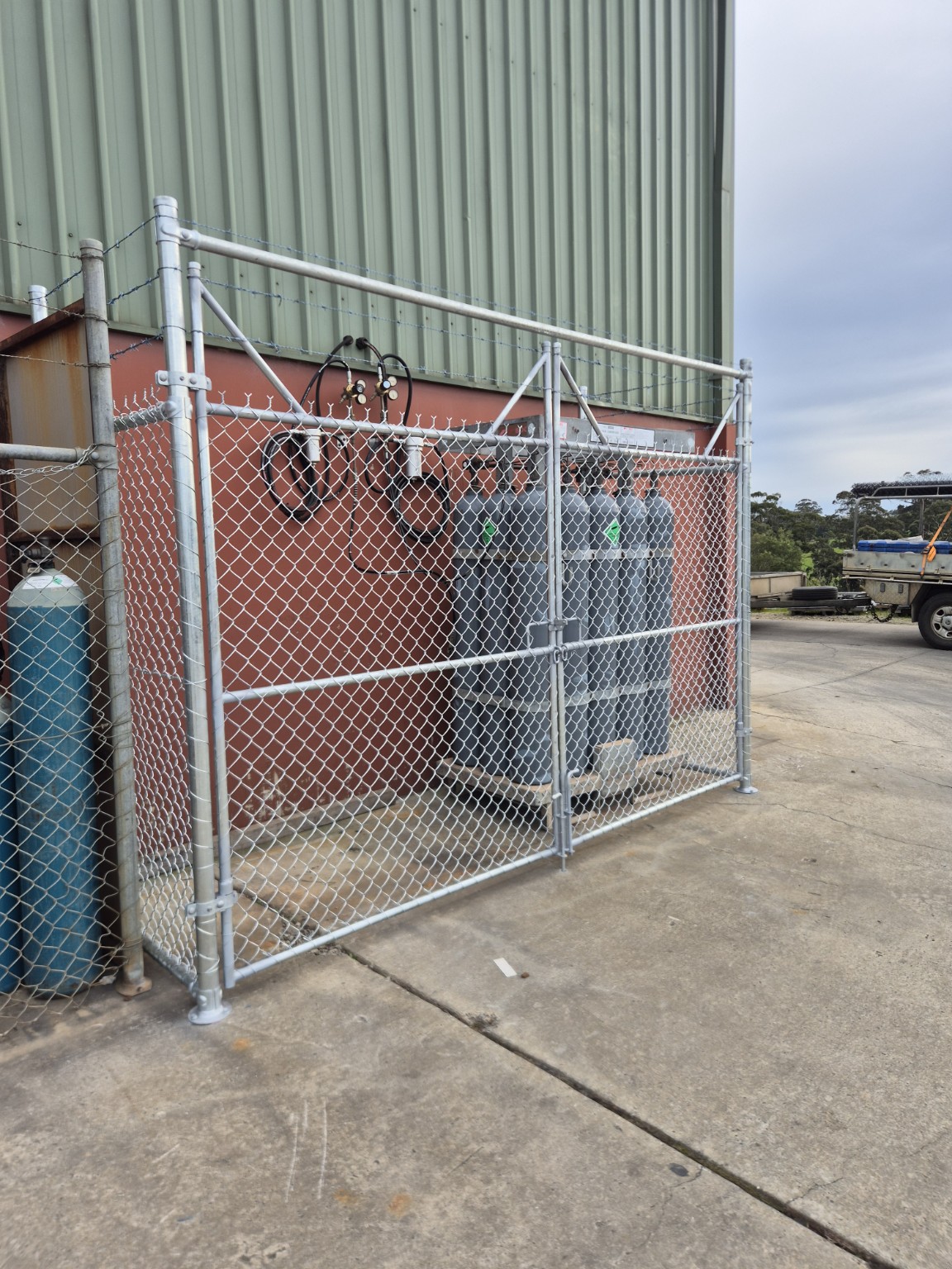 Galvanised double access gates with chain mesh and barbed wire in front of gas cylinders at Burra Sheetmetal