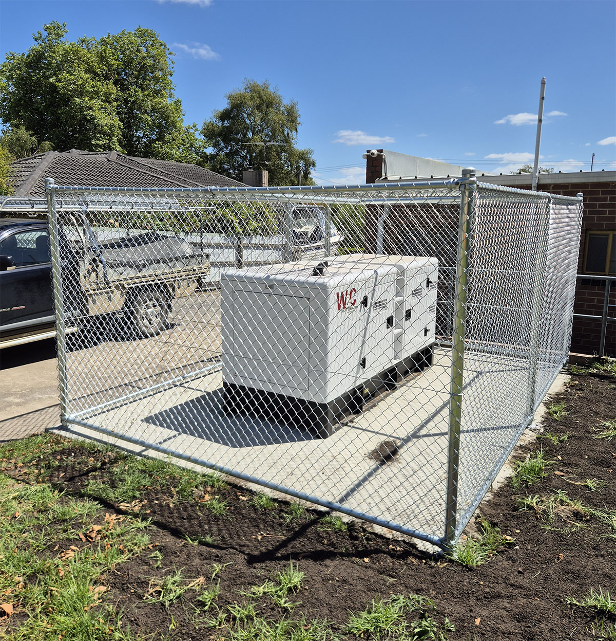 Galvanised chain mesh enclosure around wall-mounted services and equipment