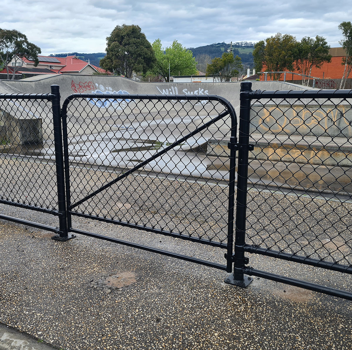 Black security gate with razor wire topping at an industrial site entry