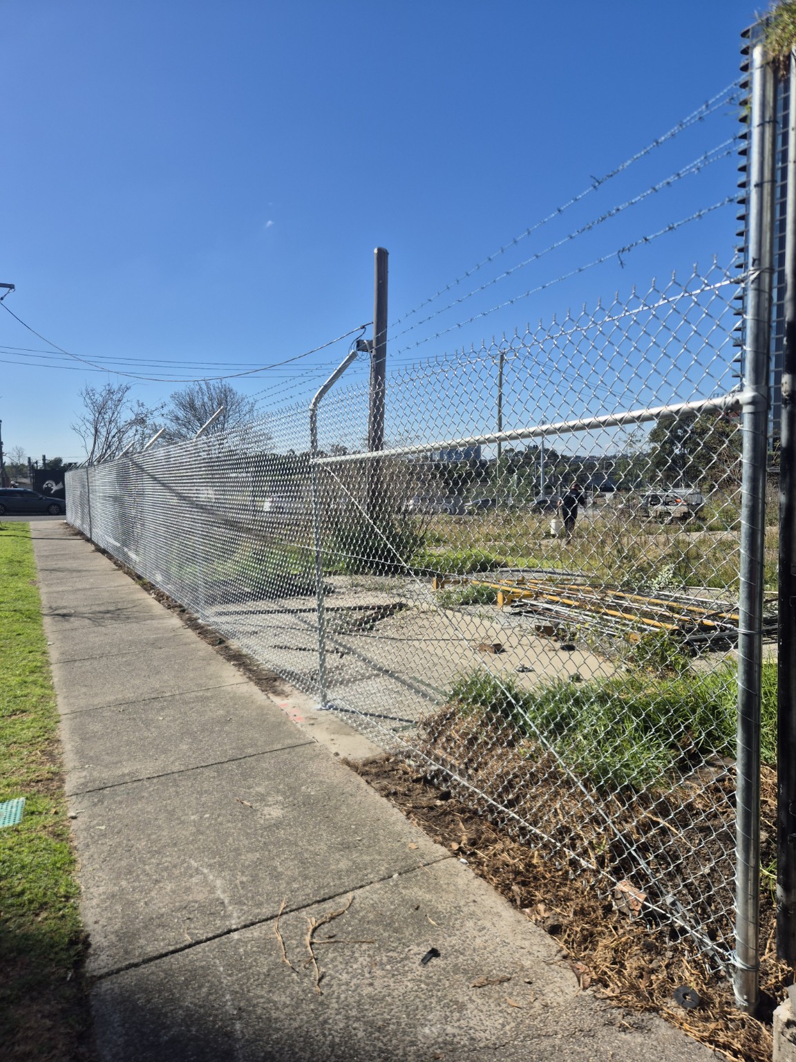 Completed galvanised chain mesh security fence beside the footpath at the Growland site in Footscray