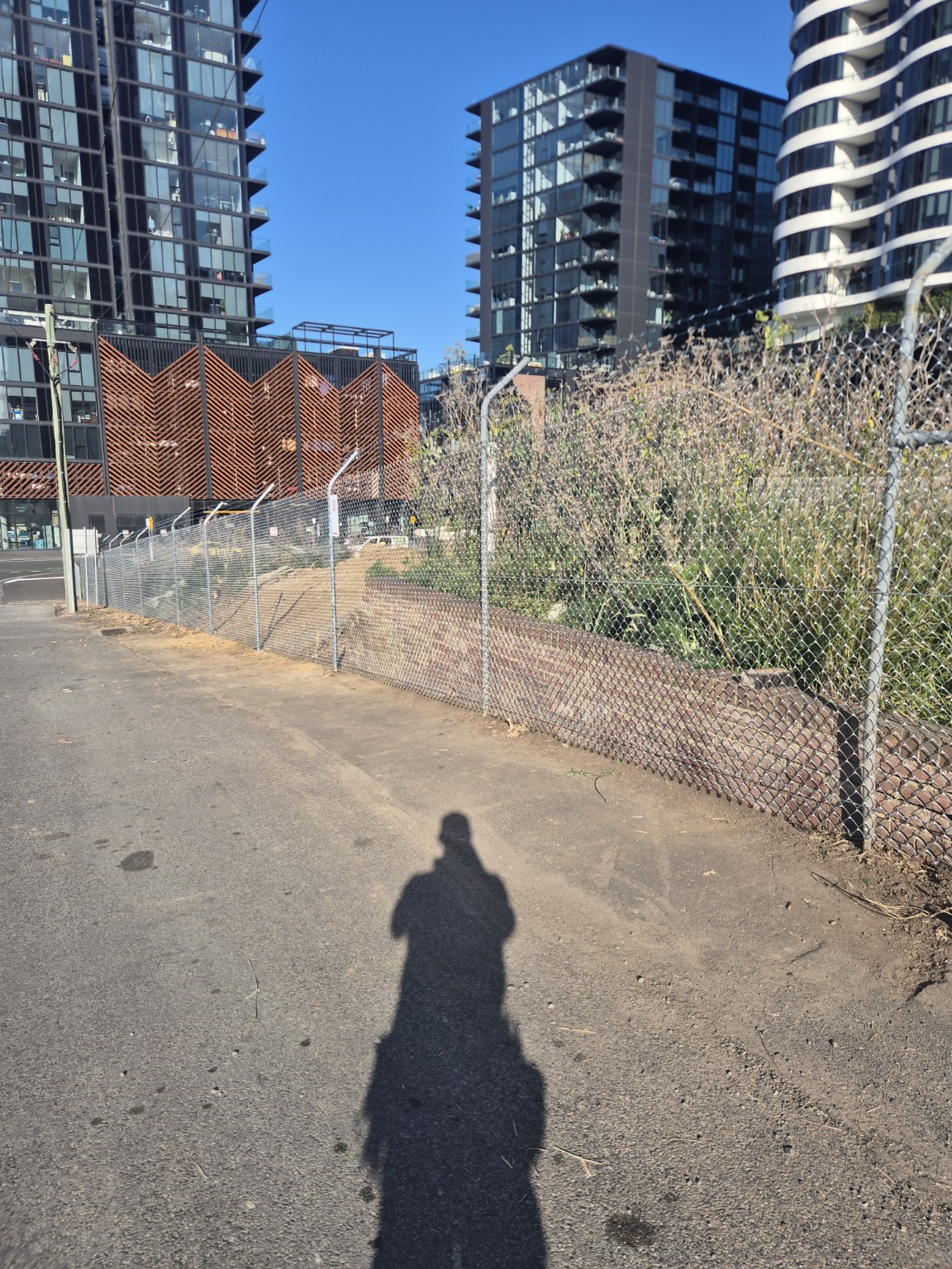 Renovated Footscray boundary fence with cranked posts and barbed wire following the sloping footpath