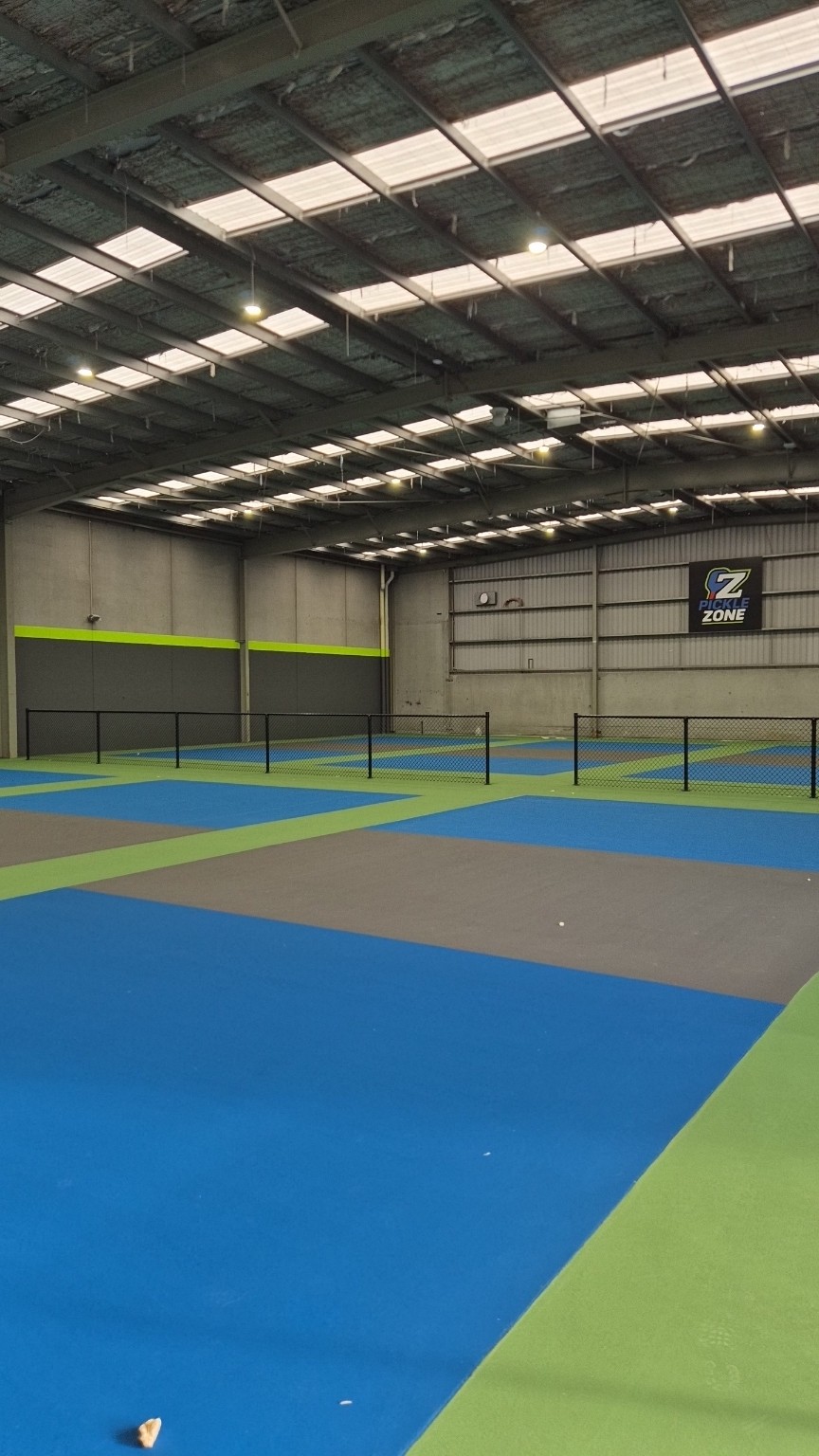 Completed black chain mesh court dividers across the blue and green indoor courts at Pickle Zone in Springvale