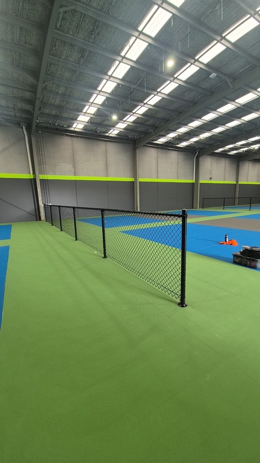 Black PVC-coated chain mesh divider with top rail and base-plated posts at Pickle Zone Springvale