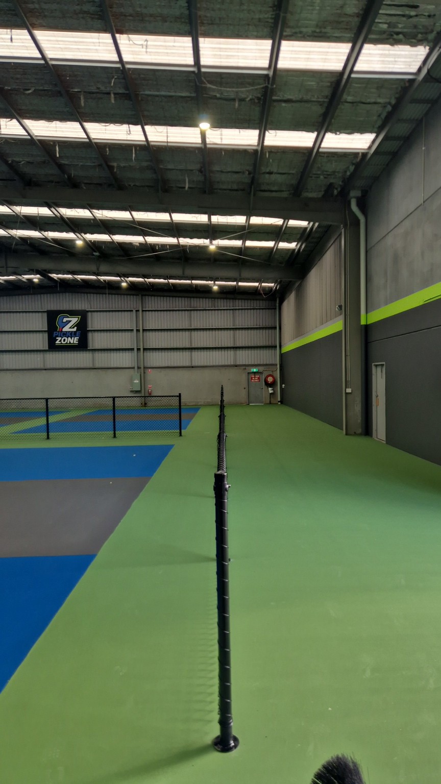 View along the completed bolt-down fence separating indoor pickleball courts from the walkway