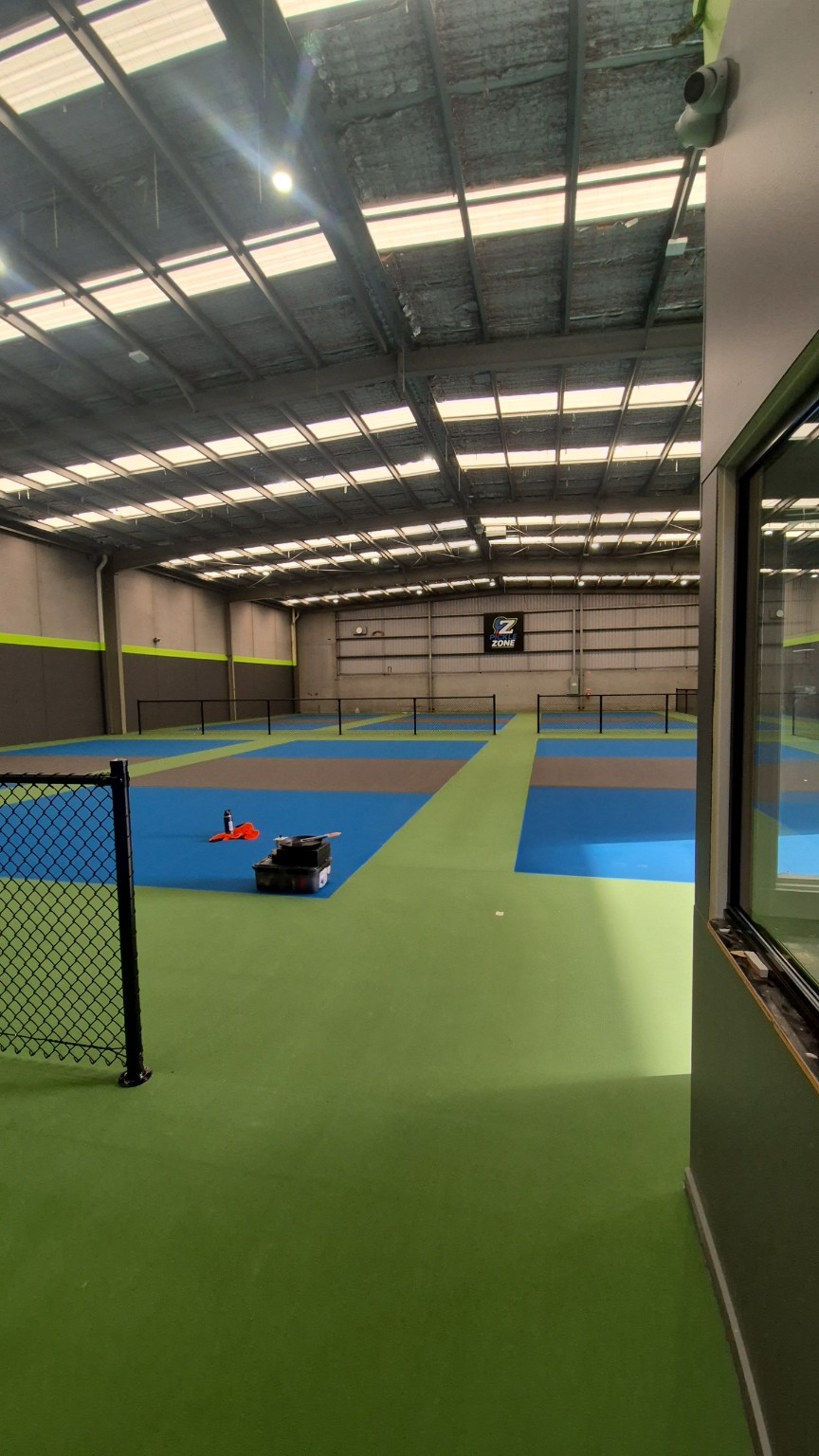 View from the entrance across the completed indoor pickleball court fencing at Pickle Zone