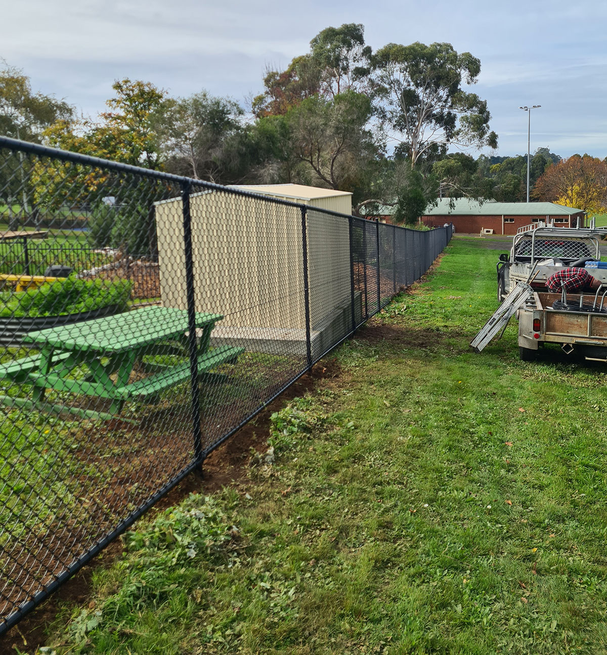 Covered school walkway enclosed with black chain mesh fencing and gate