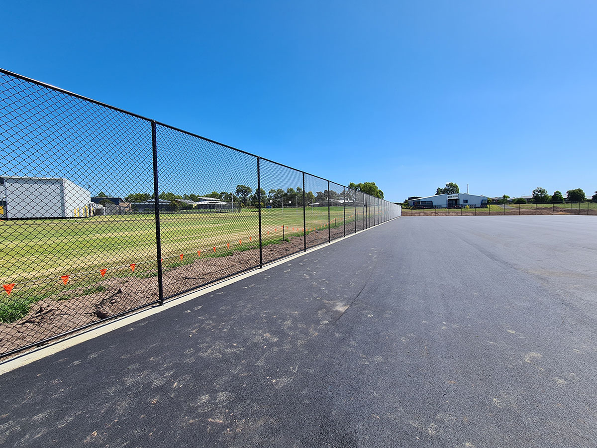Backyard basketball court with black sports fencing and hoop