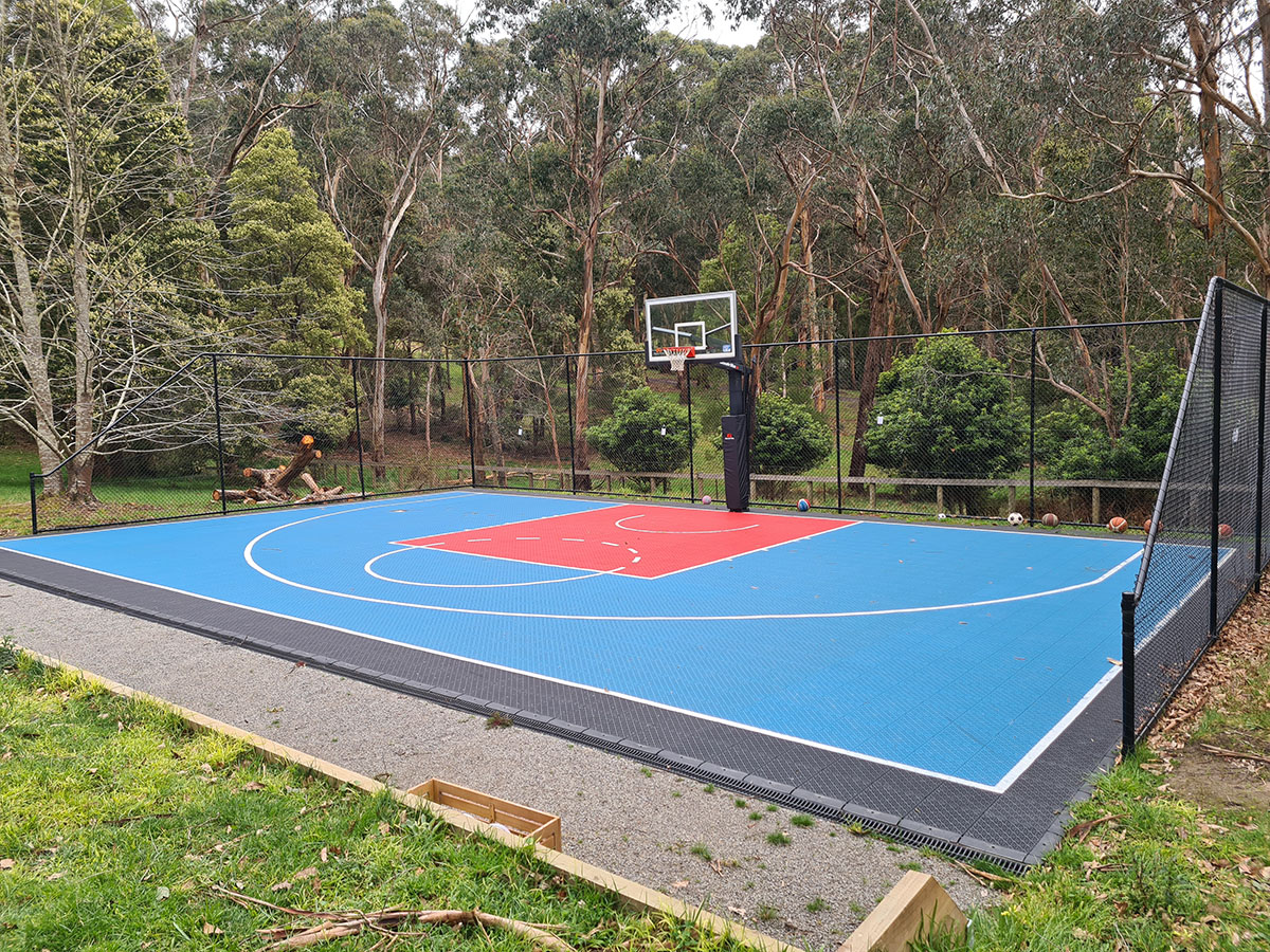 Long black chain mesh sports fencing beside asphalt court area