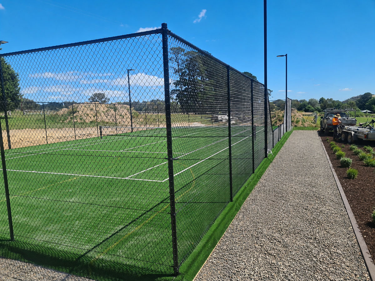Black chain mesh sports fencing beside a football oval and public reserve