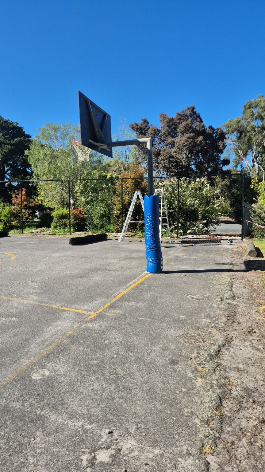New black fence framework and access gate opening during installation beside the school basketball hoop