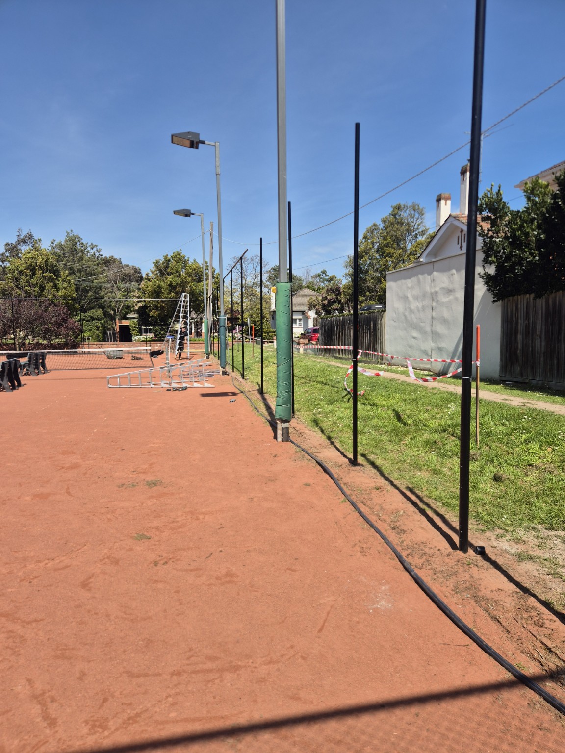 Black painted fence posts after removal of the old chain mesh at Willison Park Tennis Club